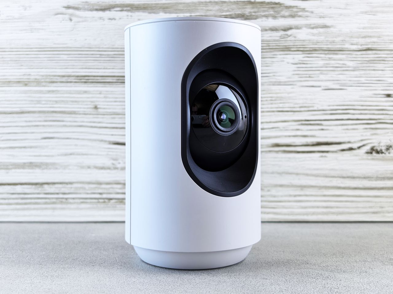 our-story Close-up of a white indoor security camera against a wooden backdrop, showcasing modern design.